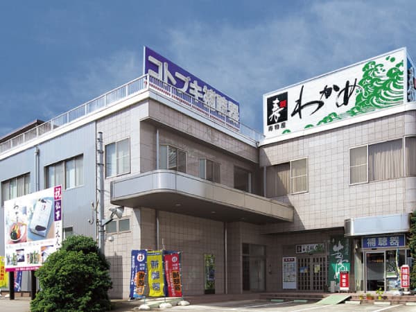 寿物産本社ビルの外観。1階の向かって左側が食品工場直販店、右側がコトブキ補聴器